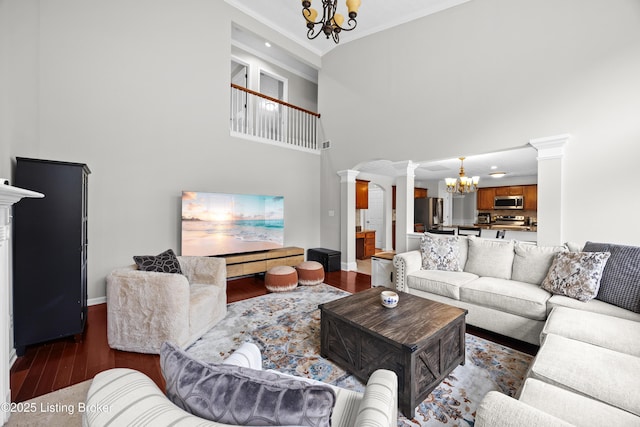 living room featuring a high ceiling, wood finished floors, decorative columns, and a notable chandelier