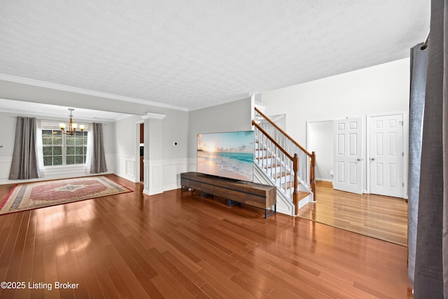 foyer featuring a wainscoted wall, wood finished floors, stairs, a textured ceiling, and a chandelier