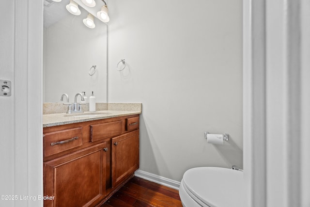 bathroom with toilet, wood-type flooring, vanity, and baseboards