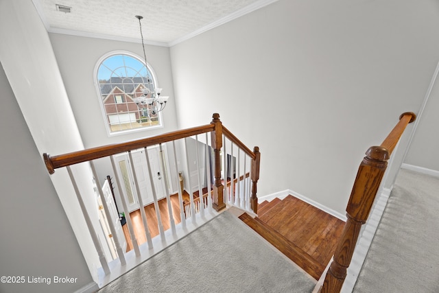 stairway with visible vents, an inviting chandelier, ornamental molding, a textured ceiling, and baseboards