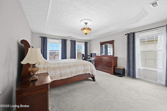 carpeted bedroom with a raised ceiling, visible vents, and a textured ceiling