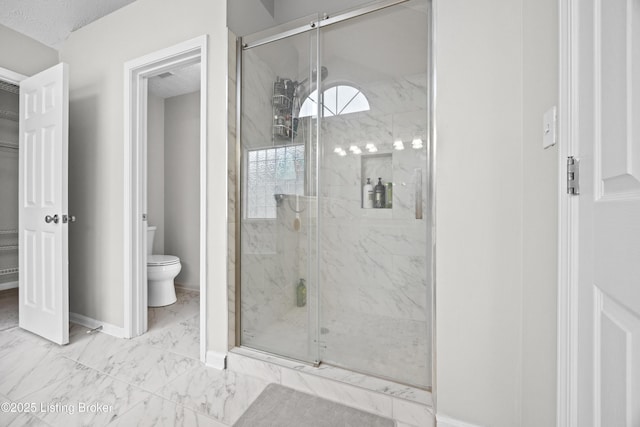 bathroom with marble finish floor, a marble finish shower, toilet, and baseboards