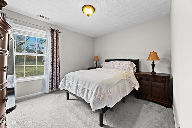 bedroom featuring baseboards, carpet flooring, visible vents, and a textured ceiling