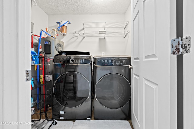 laundry area with laundry area, a textured ceiling, and washing machine and clothes dryer