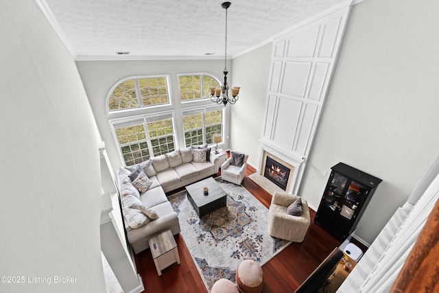 living area with crown molding, a textured ceiling, and wood finished floors