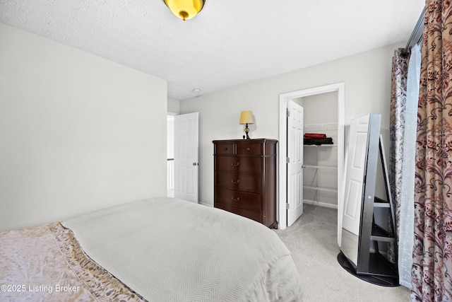 carpeted bedroom featuring a textured ceiling, a spacious closet, and a closet