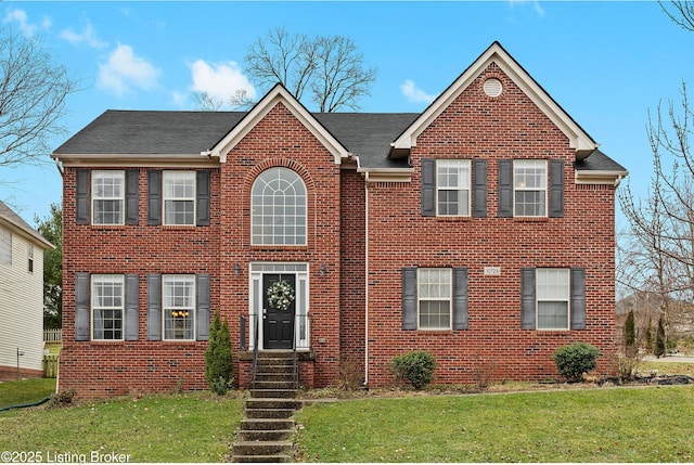 view of front of home featuring entry steps, brick siding, and a front lawn