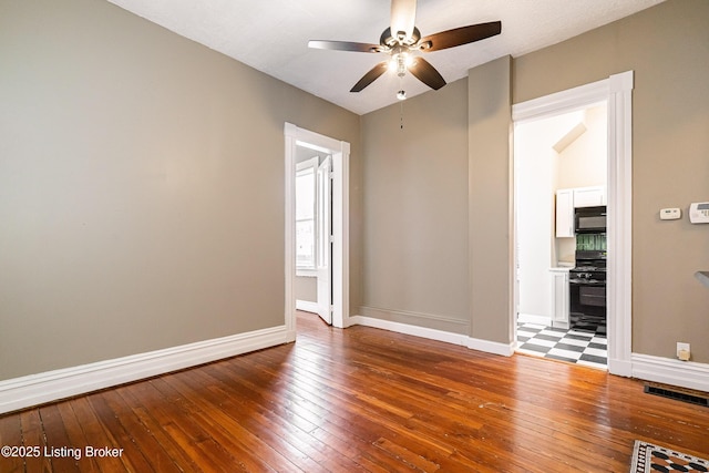 spare room with ceiling fan, visible vents, hardwood / wood-style flooring, and baseboards
