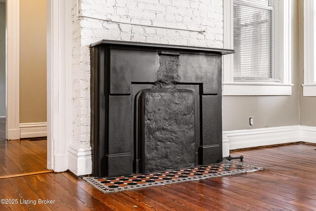 room details featuring a fireplace with flush hearth, baseboards, and wood finished floors