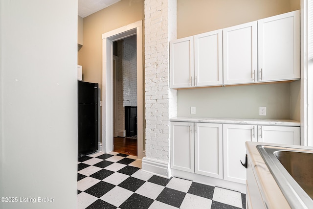 kitchen featuring light floors, light countertops, freestanding refrigerator, and white cabinetry