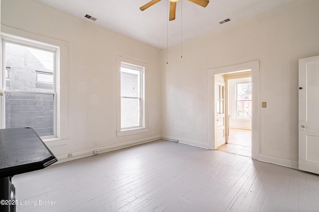 spare room featuring light wood finished floors, visible vents, and baseboards
