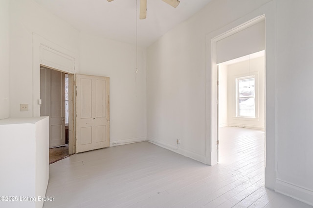 empty room featuring light wood-style floors, baseboards, and a ceiling fan