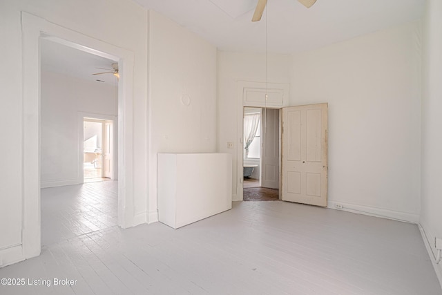 empty room featuring baseboards, a ceiling fan, and wood finished floors