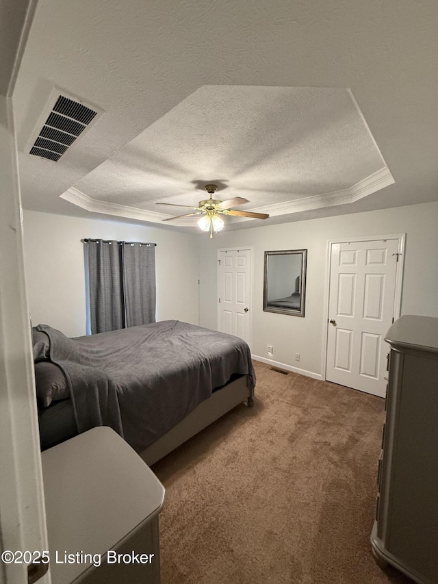 carpeted bedroom featuring a tray ceiling, visible vents, a textured ceiling, and ceiling fan