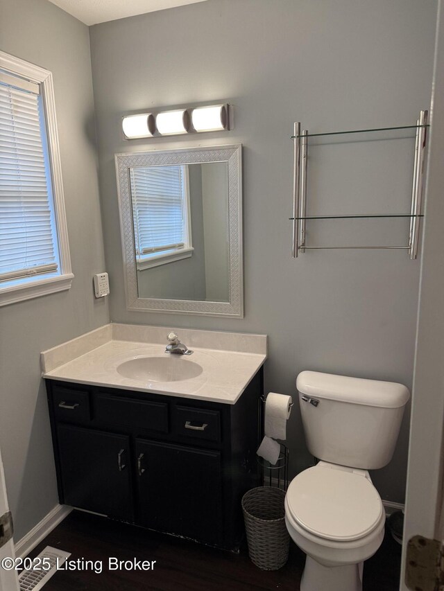 bathroom with toilet, vanity, and baseboards