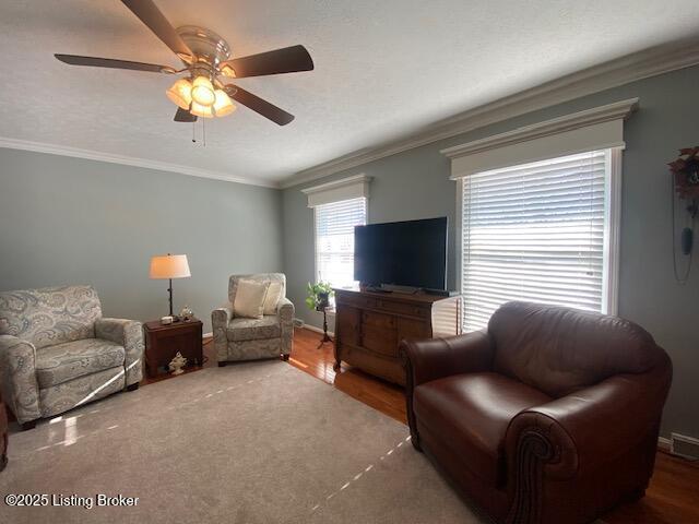 living room with ceiling fan, ornamental molding, and baseboards