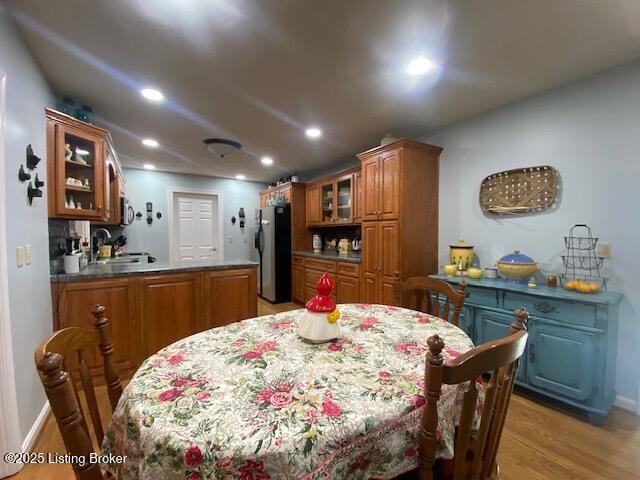 dining room with baseboards, wet bar, light wood-type flooring, and recessed lighting