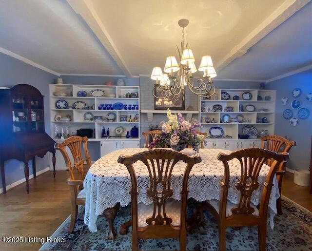 dining area featuring a chandelier, crown molding, baseboards, and wood finished floors