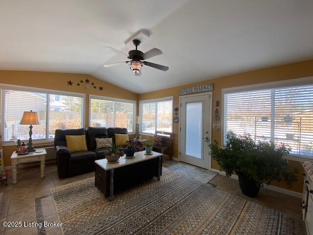 living area with a ceiling fan, a wealth of natural light, and vaulted ceiling