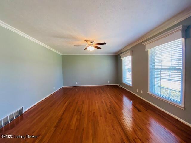 empty room featuring visible vents, baseboards, a ceiling fan, wood finished floors, and ornamental molding