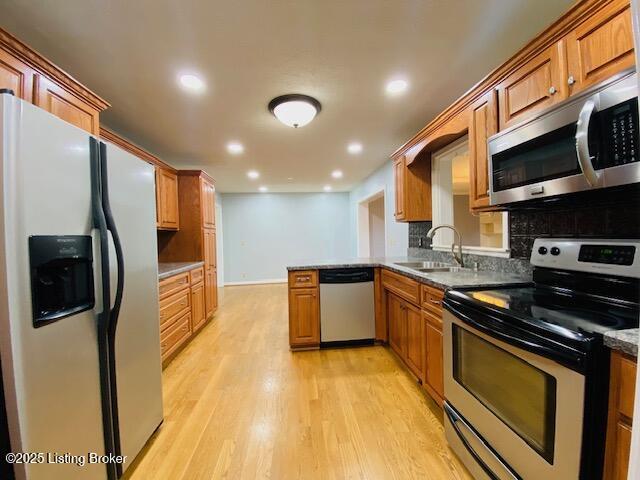 kitchen with recessed lighting, backsplash, a sink, light wood-style floors, and appliances with stainless steel finishes