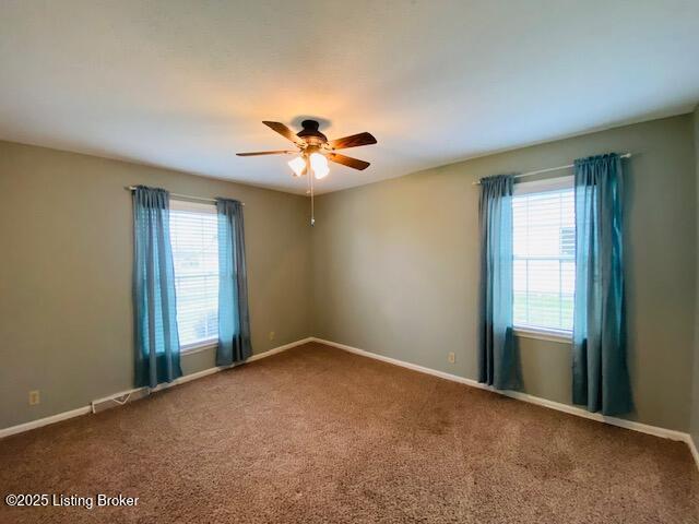 carpeted empty room with ceiling fan and baseboards