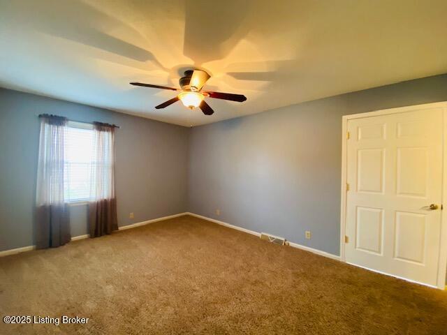 spare room featuring ceiling fan, carpet floors, and baseboards