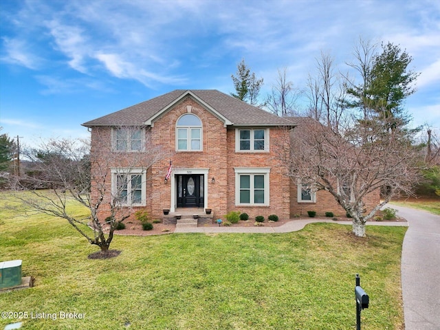 view of front of house with a shingled roof, cooling unit, brick siding, and a front lawn