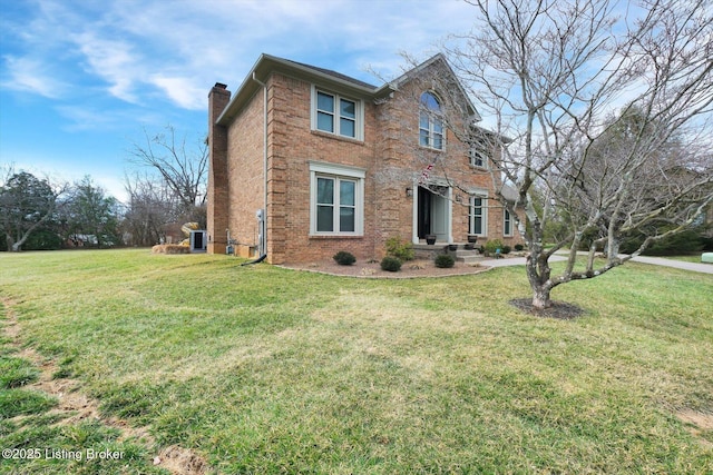 view of front of house featuring brick siding, a chimney, central AC, and a front yard