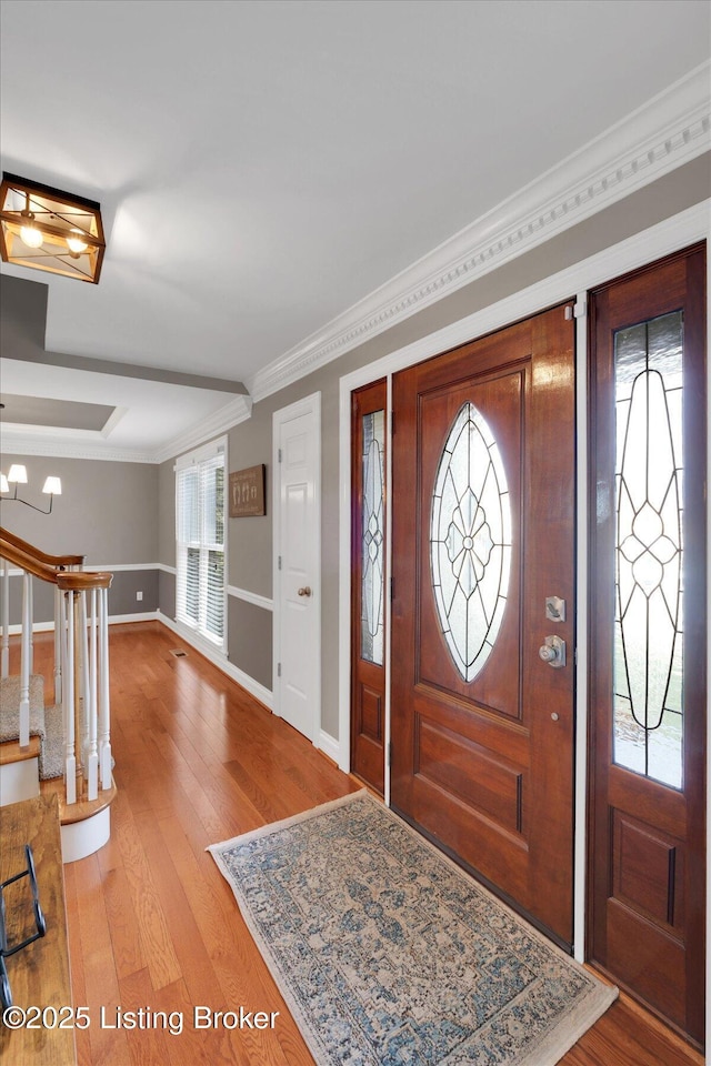 entryway featuring ornamental molding, light wood-type flooring, stairway, and baseboards