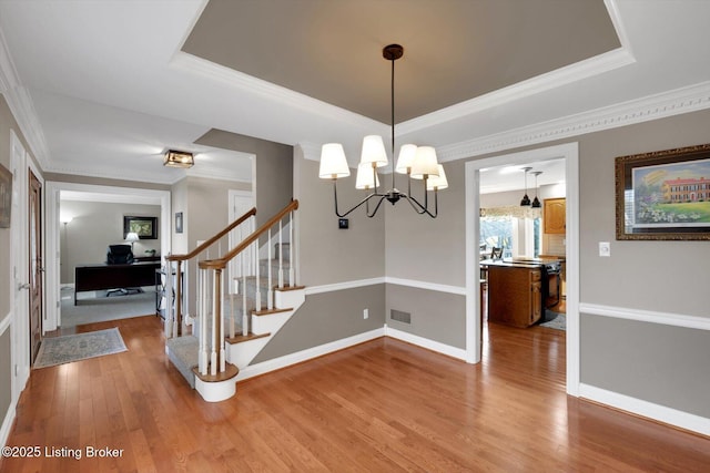 dining area with crown molding, a raised ceiling, visible vents, light wood-type flooring, and baseboards