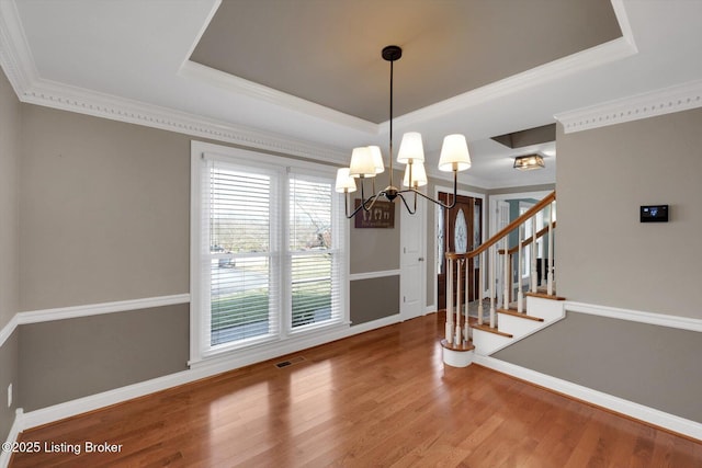 dining room featuring a tray ceiling, stairway, wood finished floors, and visible vents