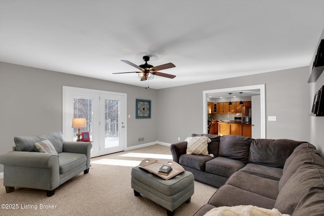 living area featuring light colored carpet, ceiling fan, visible vents, and baseboards