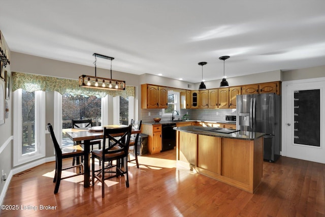 kitchen with light wood-style flooring, decorative backsplash, a sink, a kitchen island, and black appliances