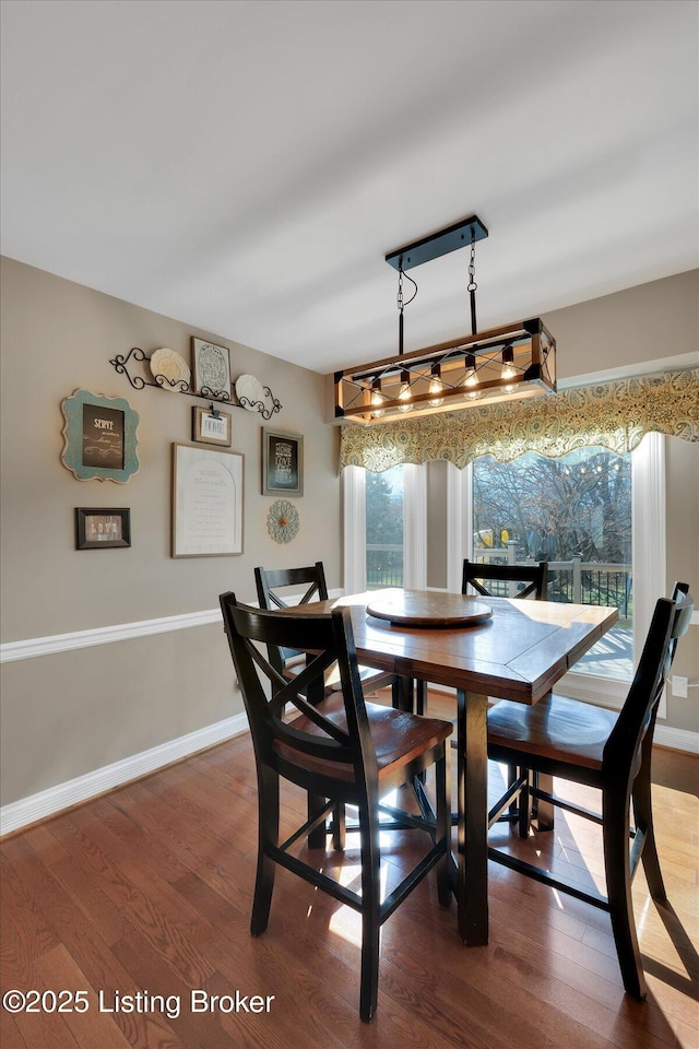 dining space featuring track lighting, wood finished floors, and baseboards