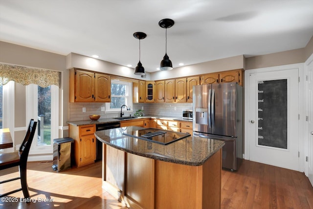 kitchen featuring appliances with stainless steel finishes, light wood-type flooring, a sink, and tasteful backsplash