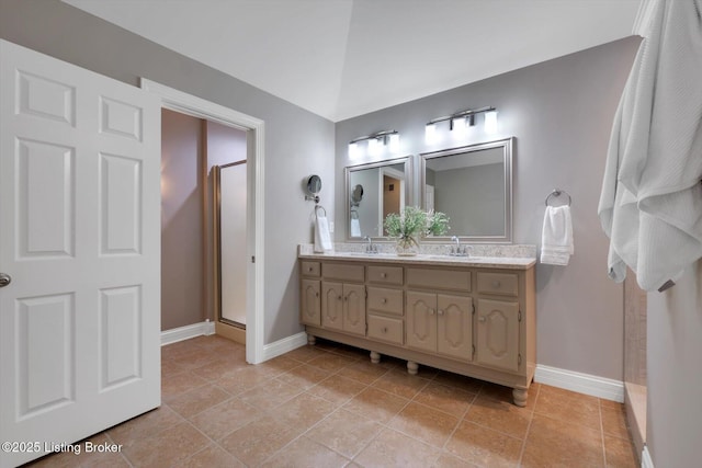 full bathroom with a stall shower, a sink, baseboards, and double vanity