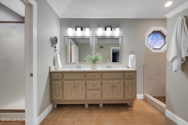 bathroom featuring tile patterned flooring, a sink, baseboards, double vanity, and walk in shower