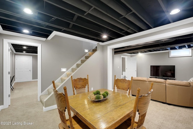 dining room featuring light colored carpet, stairway, and baseboards