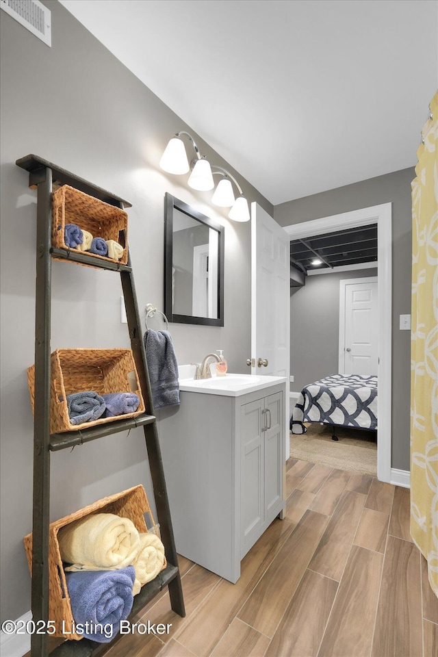 bathroom featuring wood finish floors, visible vents, vanity, and baseboards