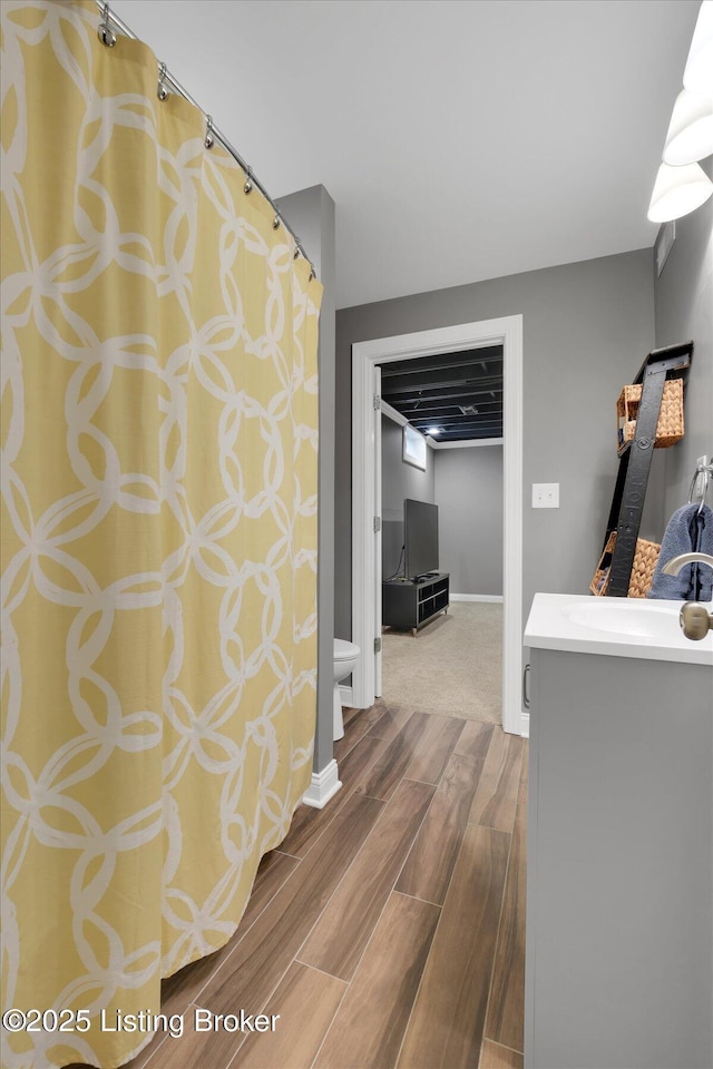 corridor featuring wood finish floors, a sink, and baseboards