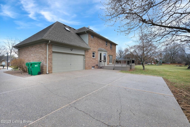 view of side of home featuring driveway, a lawn, roof with shingles, an attached garage, and brick siding