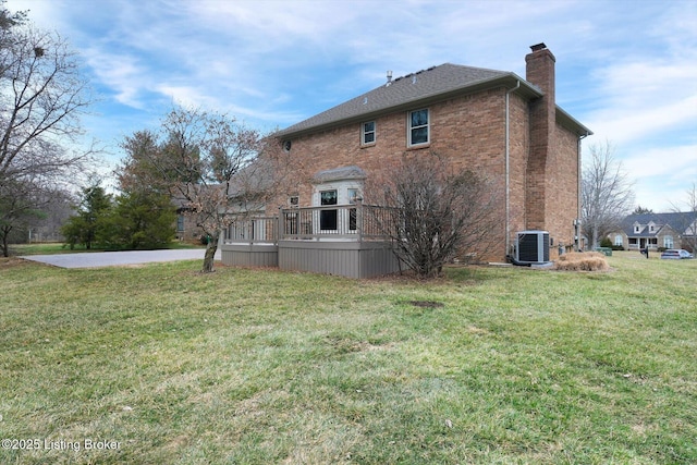 view of side of property featuring a deck, a yard, brick siding, and a chimney