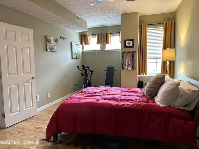 bedroom featuring a textured ceiling, visible vents, light wood-style flooring, and baseboards