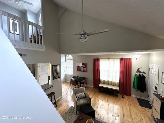 living room with baseboards, visible vents, a ceiling fan, wood-type flooring, and high vaulted ceiling