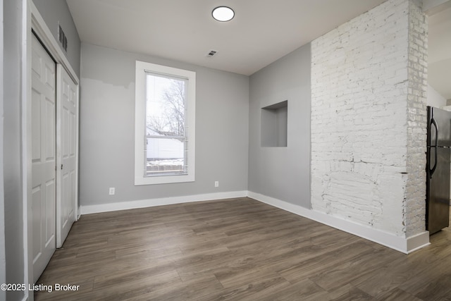 unfurnished bedroom with baseboards, visible vents, wood finished floors, and freestanding refrigerator