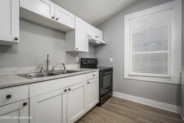 kitchen featuring light wood finished floors, white cabinets, a sink, black range with electric cooktop, and under cabinet range hood