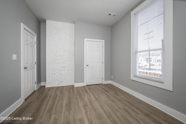 unfurnished bedroom featuring wood finished floors, visible vents, and baseboards