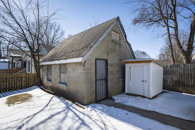 snow covered garage featuring a shed and fence