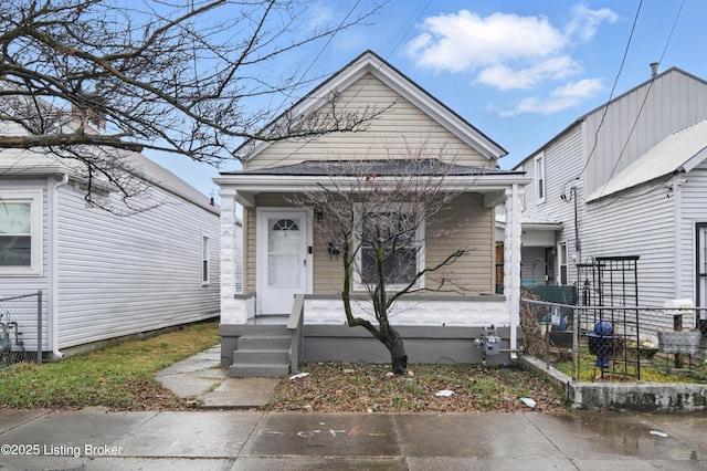 shotgun-style home with a porch and fence